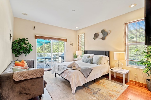 bedroom featuring multiple windows, light hardwood / wood-style floors, and access to exterior