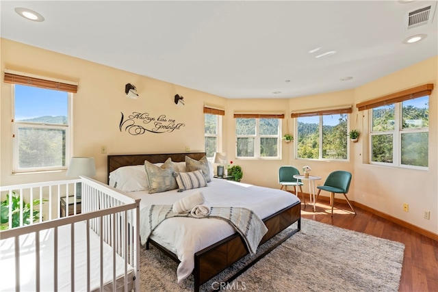 bedroom with wood-type flooring and multiple windows