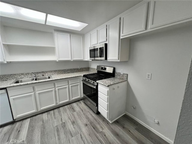 kitchen with white cabinets, sink, light stone counters, and stainless steel appliances