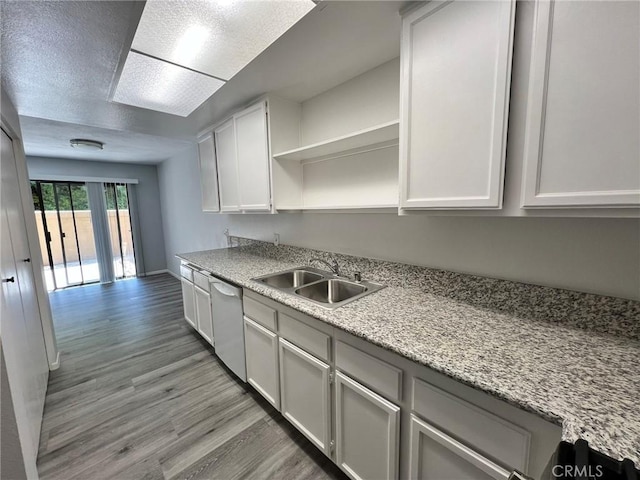 kitchen featuring light stone countertops, white cabinets, dishwasher, sink, and light hardwood / wood-style flooring