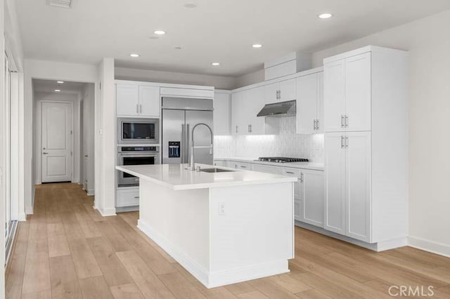 kitchen with sink, white cabinetry, a kitchen island with sink, and built in appliances