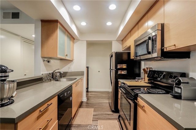 kitchen with stainless steel appliances, light brown cabinets, light wood-type flooring, and sink