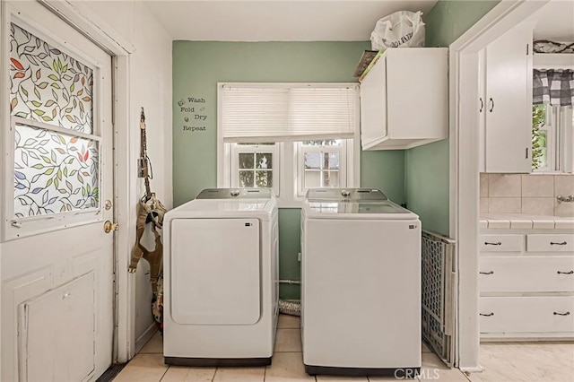 laundry room featuring cabinets, independent washer and dryer, light tile patterned floors, and a healthy amount of sunlight