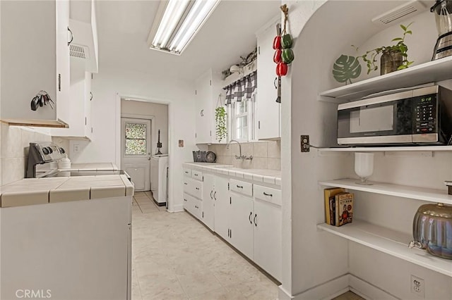 kitchen featuring sink, tasteful backsplash, separate washer and dryer, tile countertops, and white cabinets