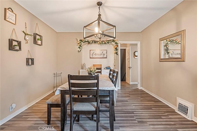 dining room with dark hardwood / wood-style flooring and a notable chandelier