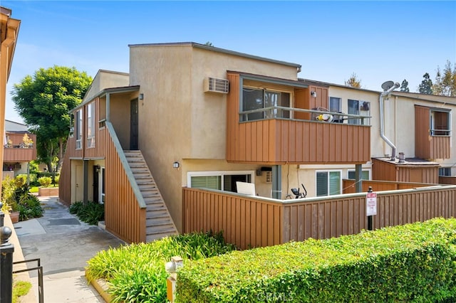 view of front of home with an AC wall unit and a balcony