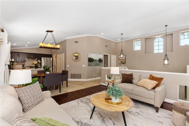 living room featuring a chandelier, crown molding, and light hardwood / wood-style flooring