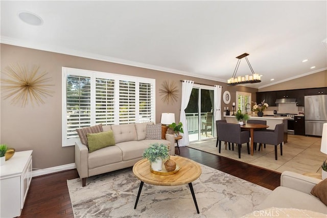 living room featuring hardwood / wood-style floors, an inviting chandelier, vaulted ceiling, and ornamental molding