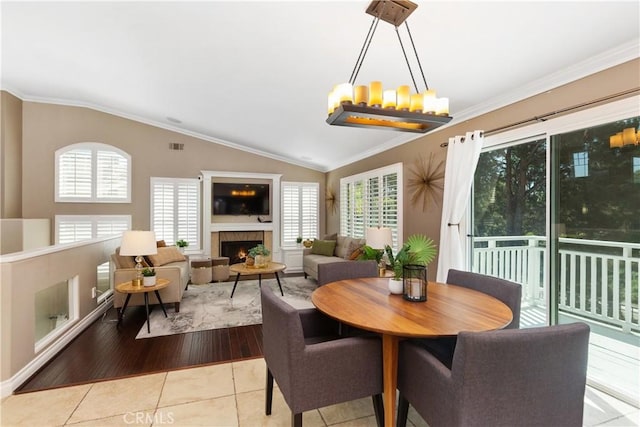 dining space with a wealth of natural light, ornamental molding, lofted ceiling, and light wood-type flooring