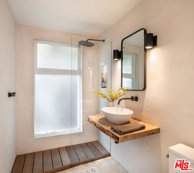 bathroom with sink, walk in shower, a healthy amount of sunlight, and toilet