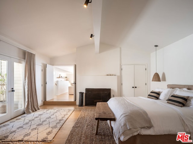 bedroom featuring access to outside, vaulted ceiling with beams, french doors, and light hardwood / wood-style floors