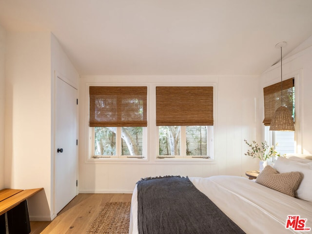 bedroom featuring lofted ceiling, multiple windows, and hardwood / wood-style flooring