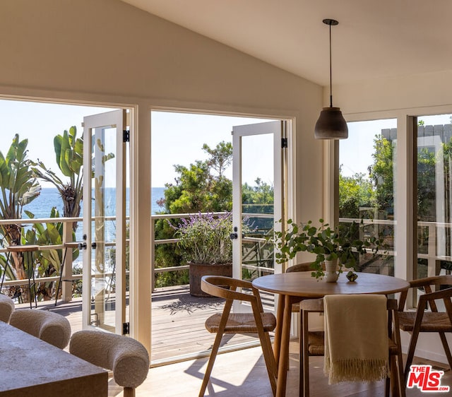 dining space featuring a water view, vaulted ceiling, and hardwood / wood-style flooring