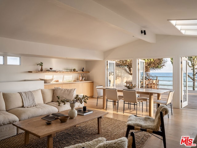 living room with vaulted ceiling with beams, light wood-type flooring, and a water view