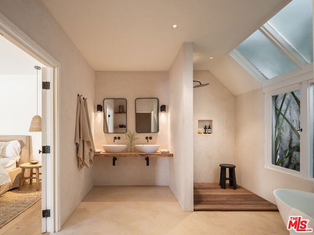 bathroom with vaulted ceiling with skylight, a tub, and vanity