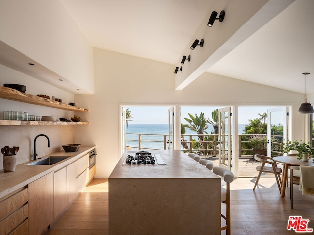 kitchen featuring pendant lighting, sink, light hardwood / wood-style flooring, a water view, and gas stovetop