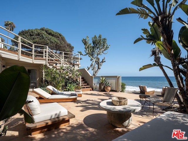 view of patio / terrace featuring a water view, a beach view, and a balcony