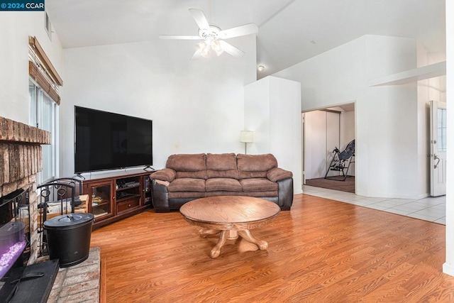 living room featuring ceiling fan, a brick fireplace, high vaulted ceiling, and light hardwood / wood-style floors