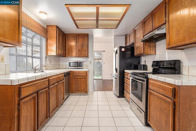 kitchen featuring light tile patterned floors, tile countertops, and stainless steel appliances