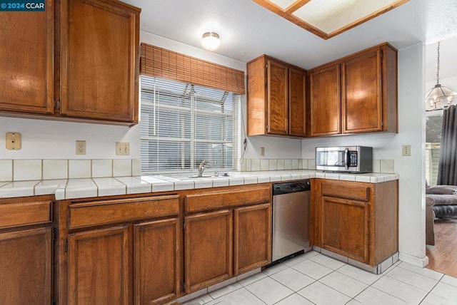 kitchen featuring light tile patterned flooring, sink, decorative light fixtures, tile counters, and stainless steel appliances