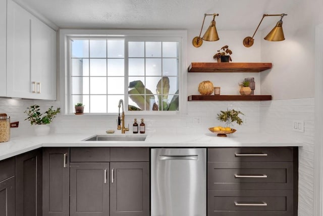 interior space featuring dishwasher, backsplash, sink, light stone countertops, and white cabinetry