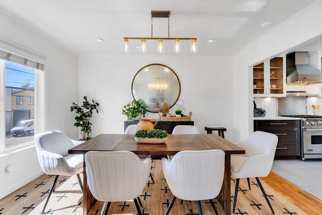 dining space with light wood-type flooring and ornamental molding