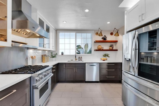 kitchen with white cabinetry, sink, wall chimney exhaust hood, stainless steel appliances, and tasteful backsplash