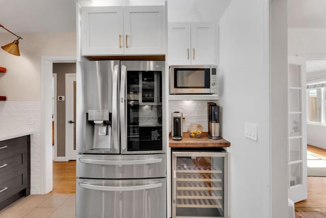 kitchen with wine cooler, decorative backsplash, appliances with stainless steel finishes, a healthy amount of sunlight, and white cabinetry