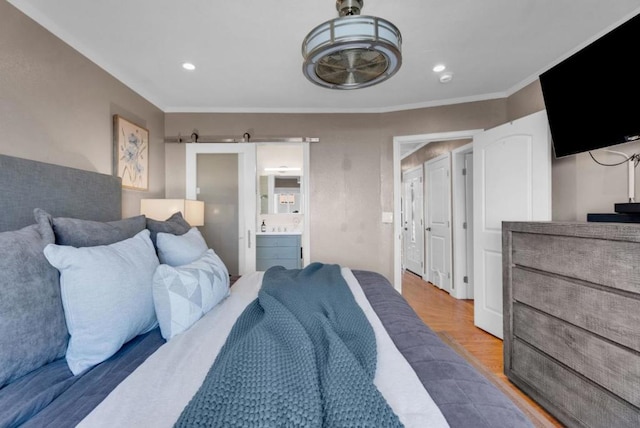 bedroom featuring hardwood / wood-style floors, crown molding, and connected bathroom