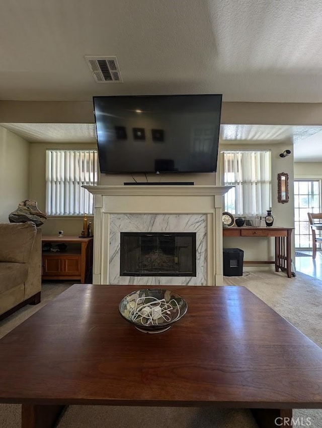 carpeted living room featuring a textured ceiling and a high end fireplace