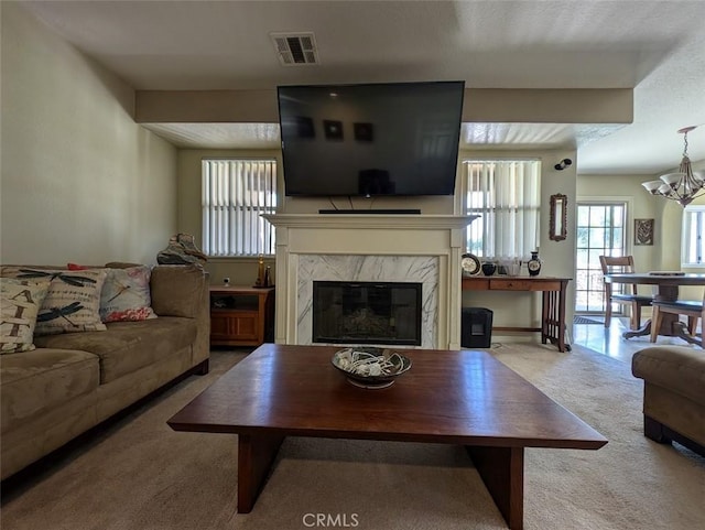 carpeted living room featuring a fireplace and a chandelier