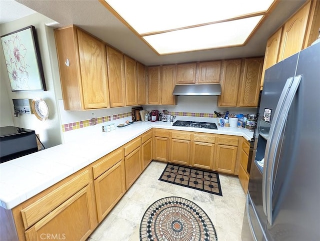 kitchen with gas stovetop, stainless steel fridge with ice dispenser, light tile patterned floors, and tasteful backsplash