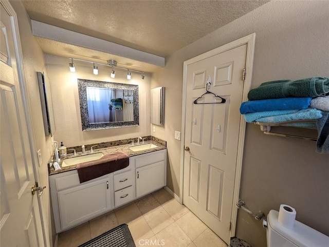 bathroom with tile patterned flooring, a textured ceiling, vanity, and toilet