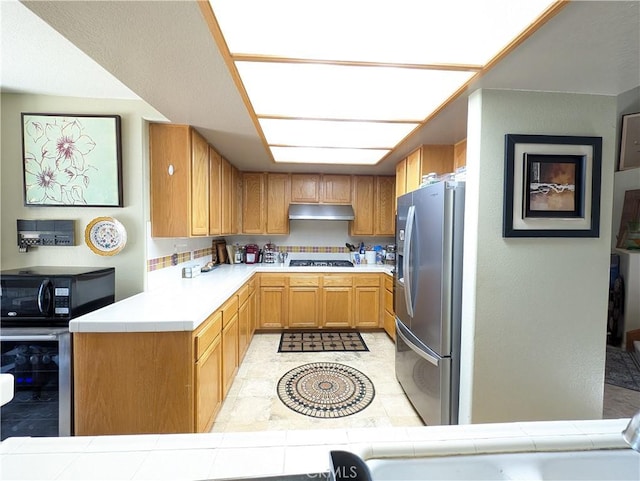 kitchen featuring kitchen peninsula, gas stovetop, beverage cooler, stainless steel fridge with ice dispenser, and tile counters