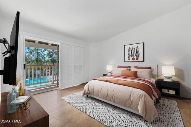 bedroom featuring lofted ceiling, access to exterior, and light wood-type flooring