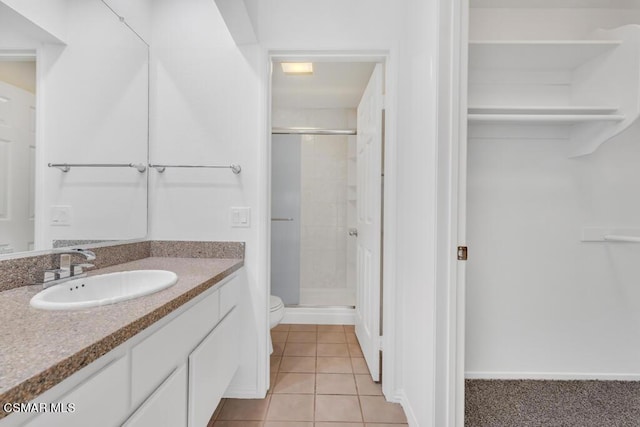 bathroom with toilet, a shower with door, vanity, and tile patterned flooring