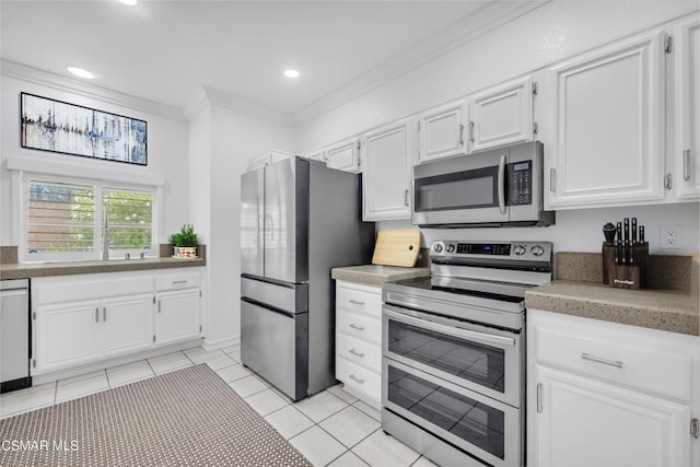 kitchen featuring ornamental molding, white cabinets, light tile patterned flooring, and appliances with stainless steel finishes