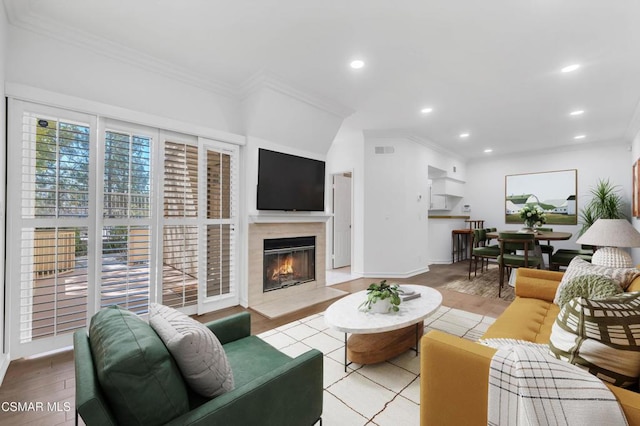 living room with crown molding, a fireplace, and light hardwood / wood-style floors