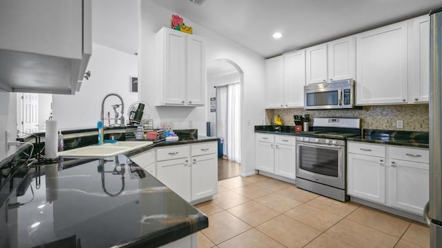 kitchen with sink, stainless steel appliances, light tile patterned floors, backsplash, and white cabinets