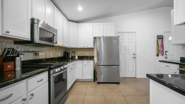 kitchen with decorative backsplash, stainless steel appliances, vaulted ceiling, white cabinetry, and light tile patterned flooring