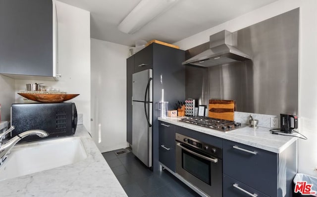 kitchen featuring dark tile patterned floors, sink, wall chimney range hood, stainless steel appliances, and light stone countertops