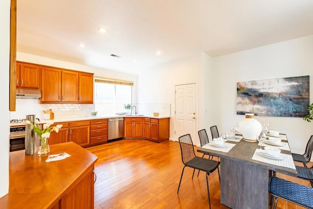 kitchen featuring decorative backsplash, dishwasher, light hardwood / wood-style flooring, and exhaust hood