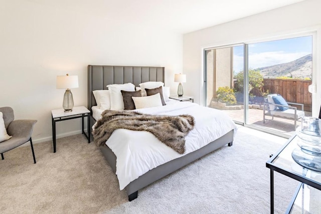 bedroom featuring light carpet, access to exterior, and a mountain view