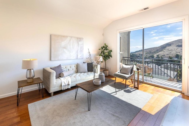 living room featuring hardwood / wood-style flooring, a mountain view, and lofted ceiling