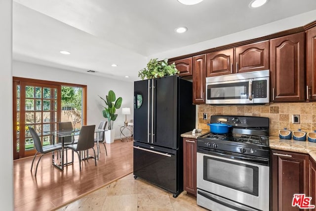 kitchen featuring decorative backsplash, light stone counters, appliances with stainless steel finishes, and dark brown cabinetry