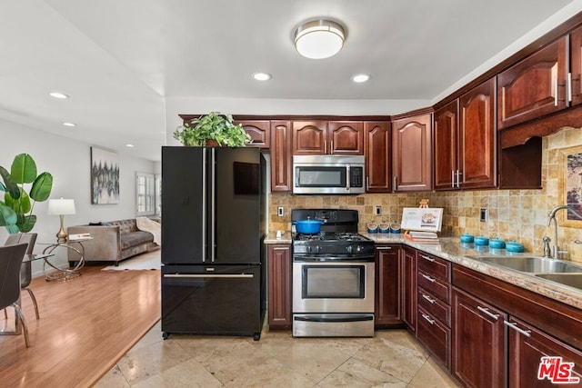 kitchen featuring light hardwood / wood-style floors, stainless steel appliances, decorative backsplash, light stone counters, and sink