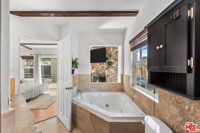 bathroom with beam ceiling, a healthy amount of sunlight, tile patterned flooring, and a relaxing tiled tub