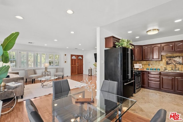 kitchen featuring decorative backsplash, electric range, black fridge, dark brown cabinetry, and sink