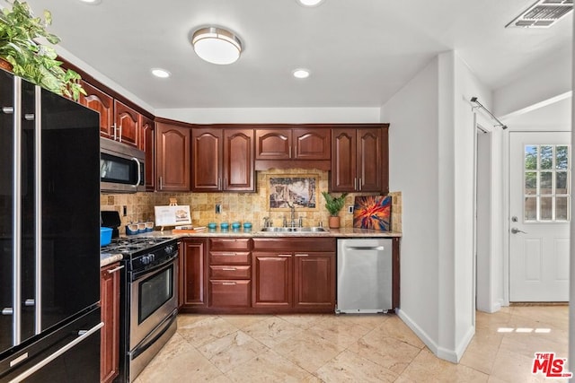 kitchen with stainless steel appliances, decorative backsplash, light stone counters, and sink