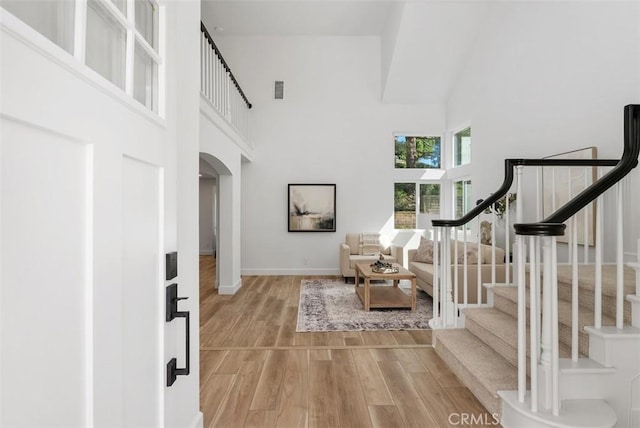 foyer entrance featuring a towering ceiling and light wood-type flooring